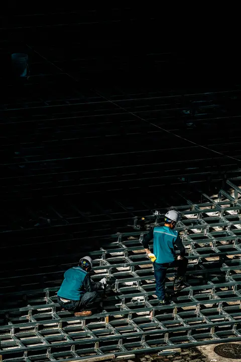 Two workers tying a steel rebar mesh before a concrete pour