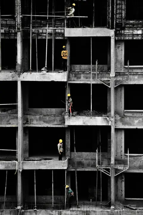 Workers in hard hats on the exposed concrete frame of a building under renovation